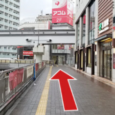 南口からデッキに出たら右に進みます。そのまま真っすぐ突き当り手前まで進んでいくと階段があるので下ります。